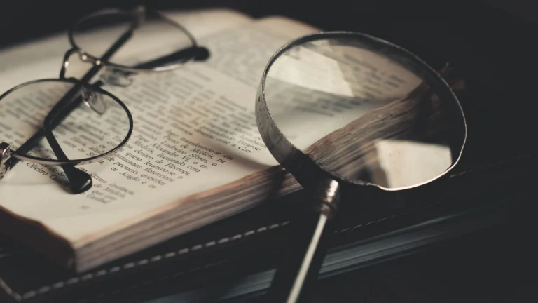 Magnifying glass and spectacles on an open research book