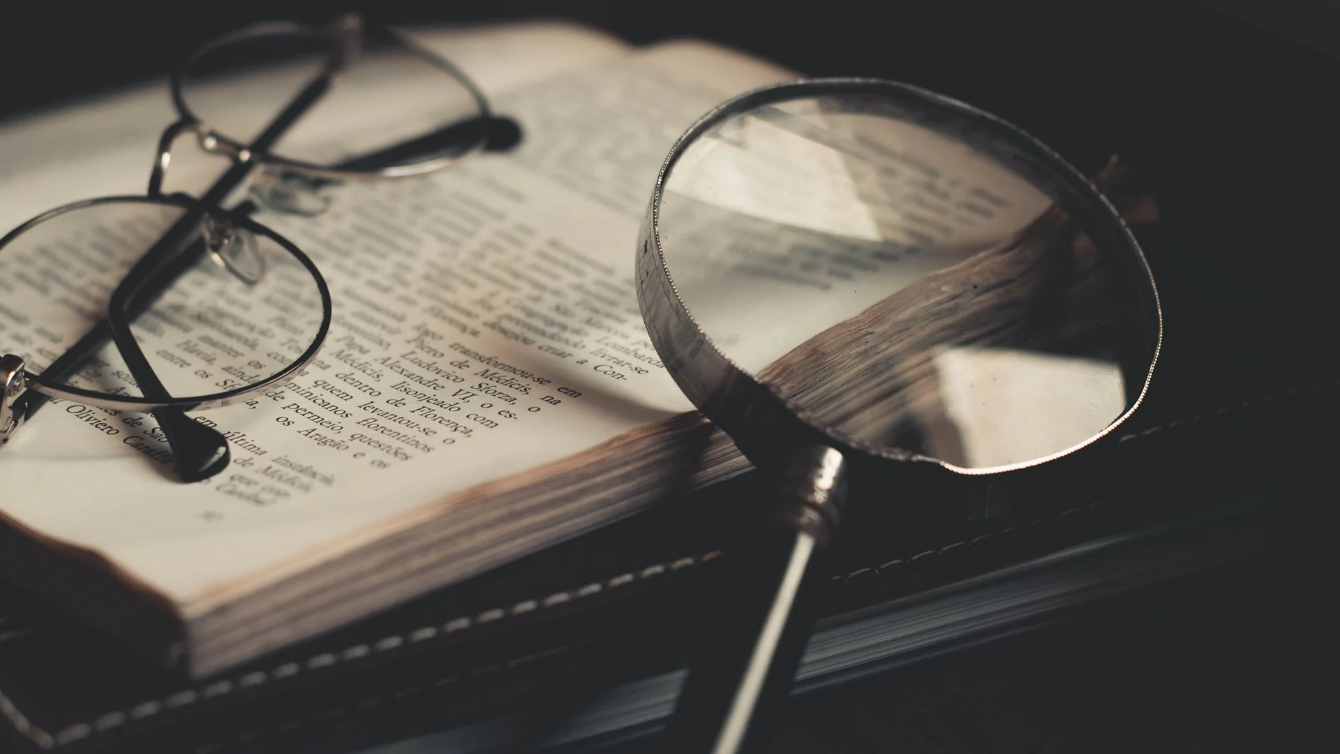 Magnifying glass and spectacles on an open research book