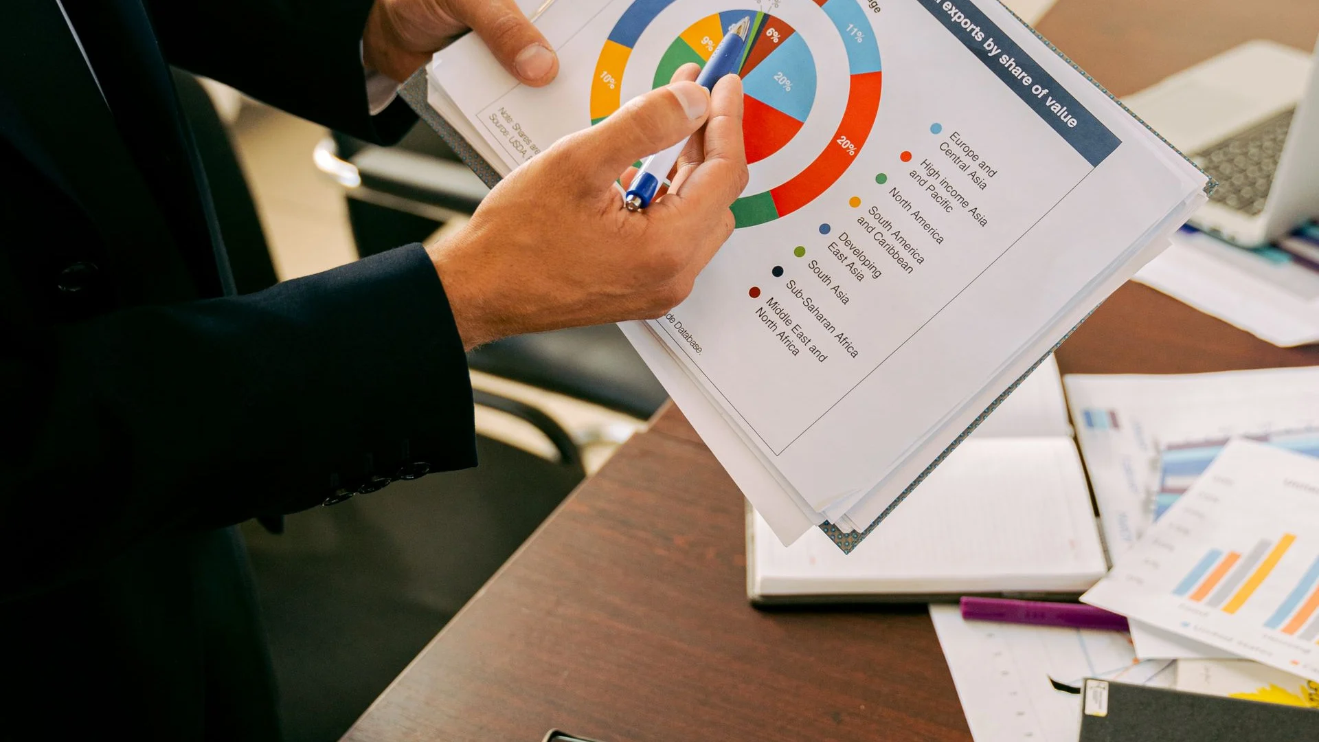 Printed charts being examined beside a notebook and laptop